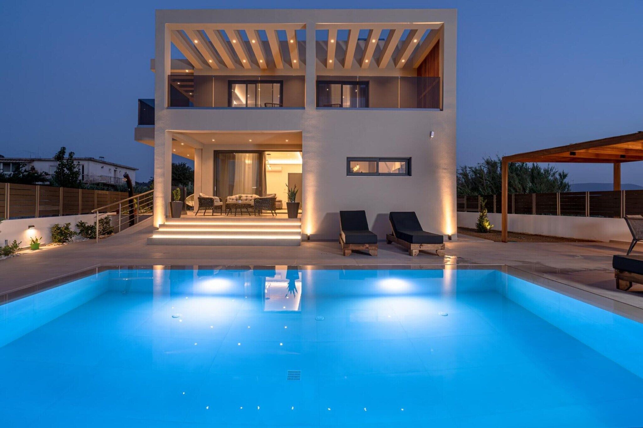 A modern two-story house with a swimming pool, outdoor seating, and a covered patio area.
