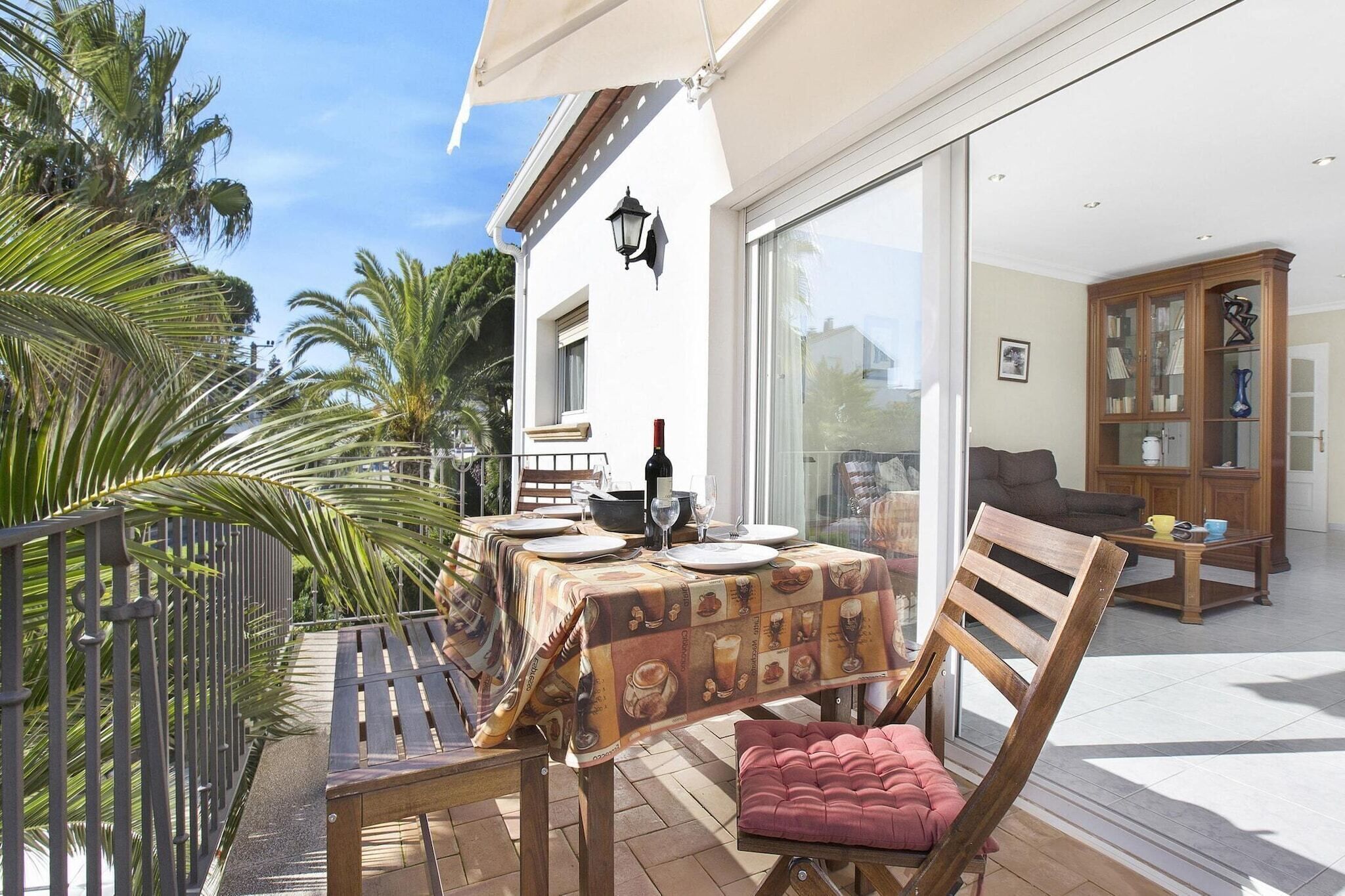 Un patio con una mesa lista para comer, una silla de madera y un banco acolchado.