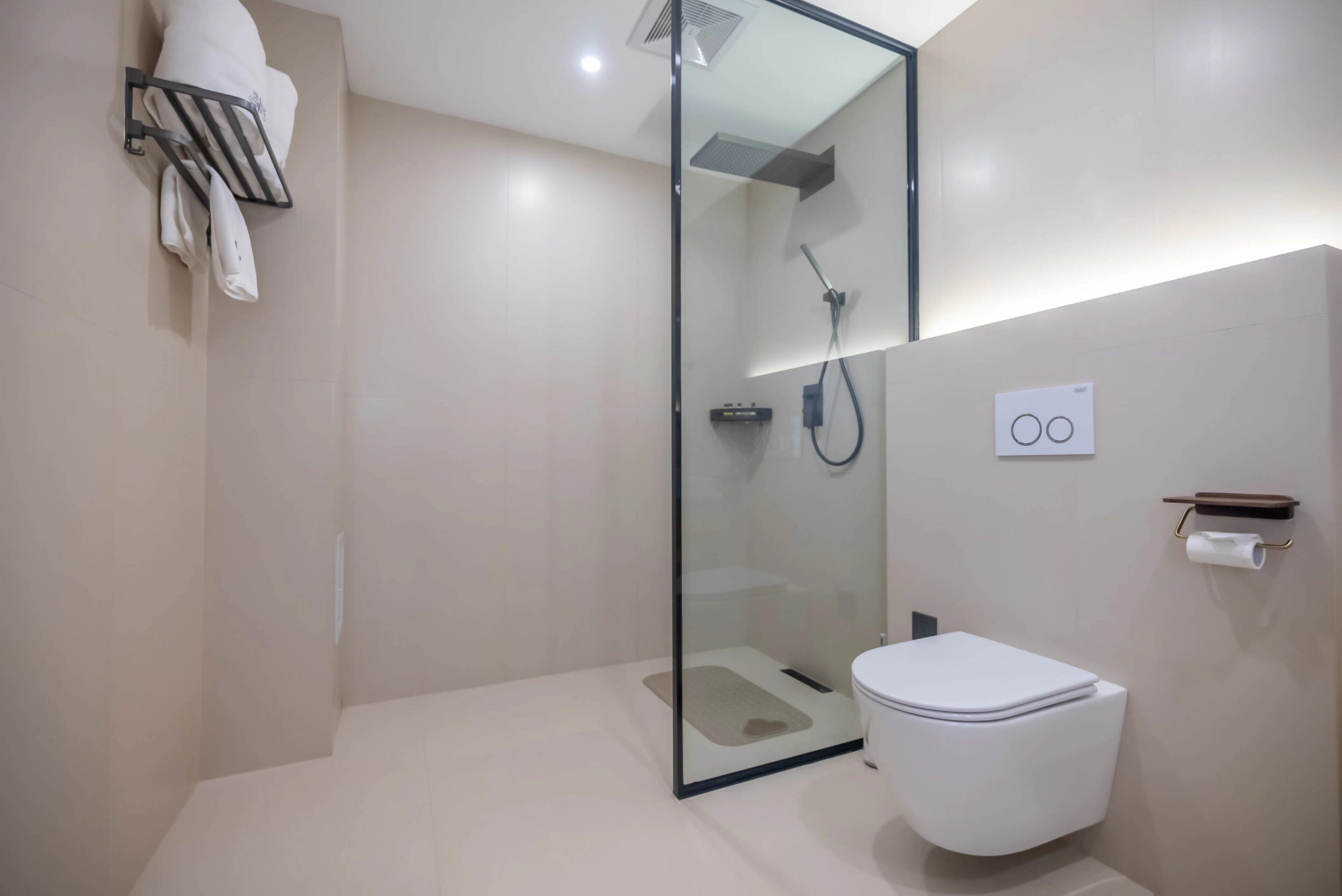 Un baño moderno con ducha de mampara de vidrio, inodoro blanco y barra para toallas.