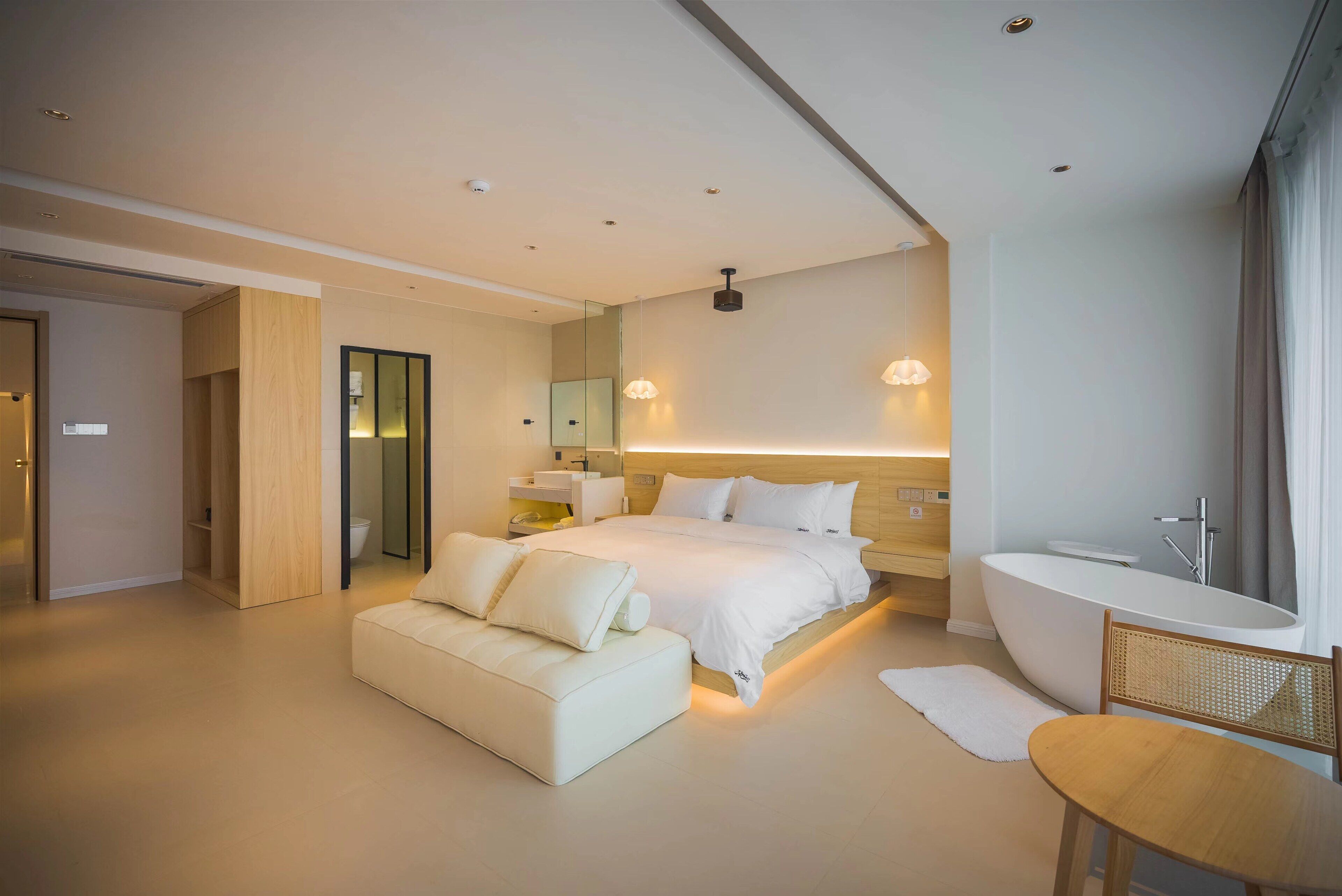 Una camera d'albergo moderna con un letto grande, un divano, una vasca da bagno e un tavolino.