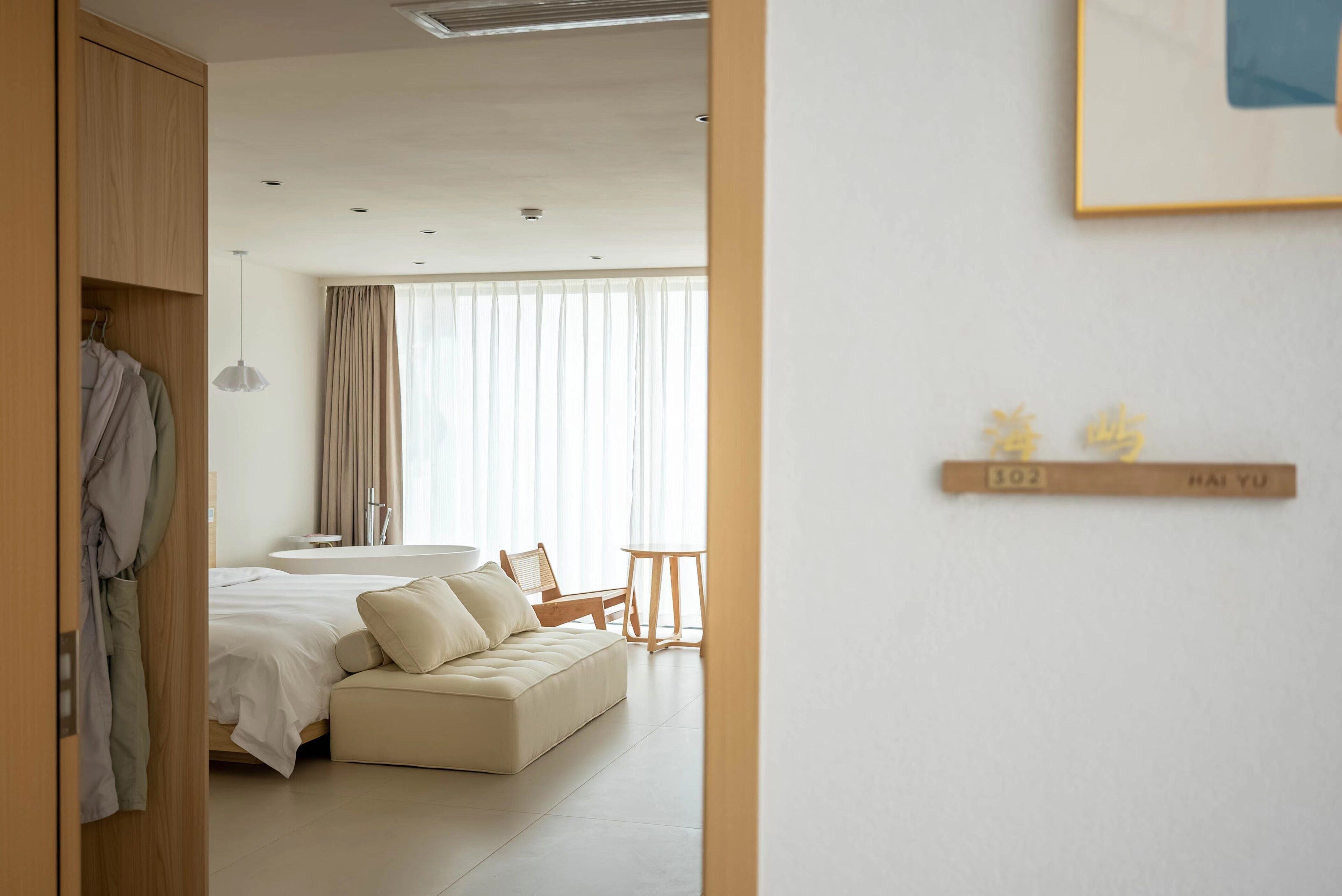 A modern hotel room with a bed, a sofa, a small table, and a bathroom.