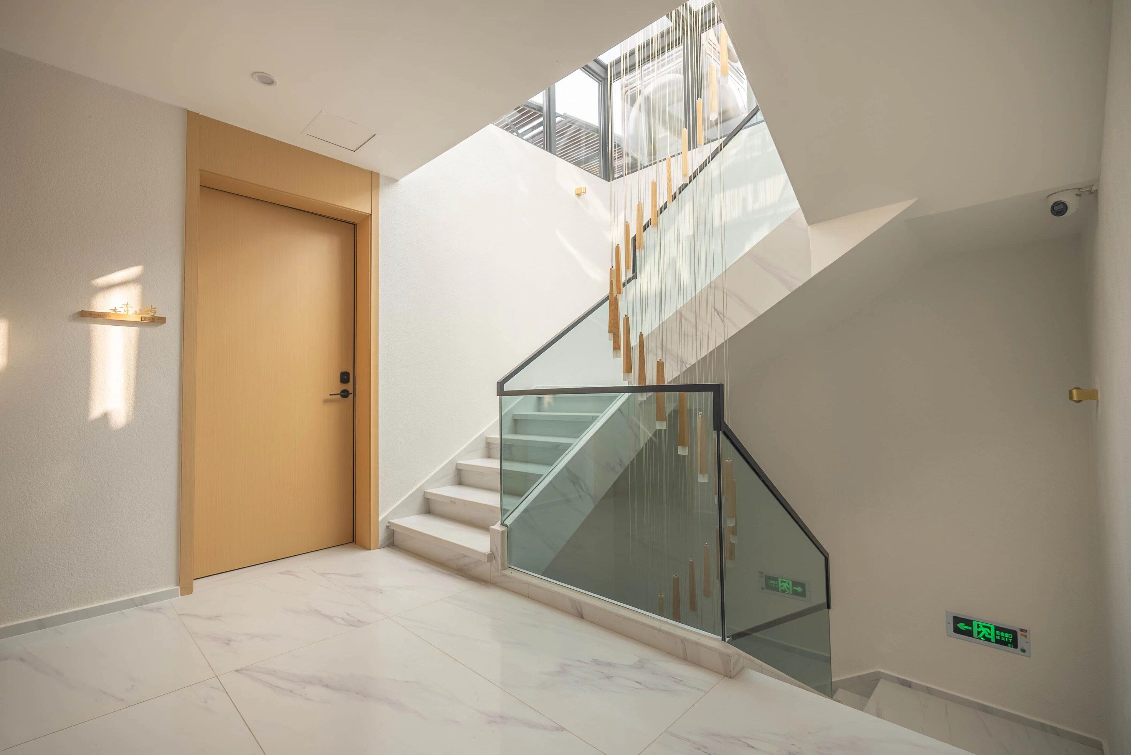 Un interno moderno con una scala in marmo, una porta in legno e una ringhiera in vetro.