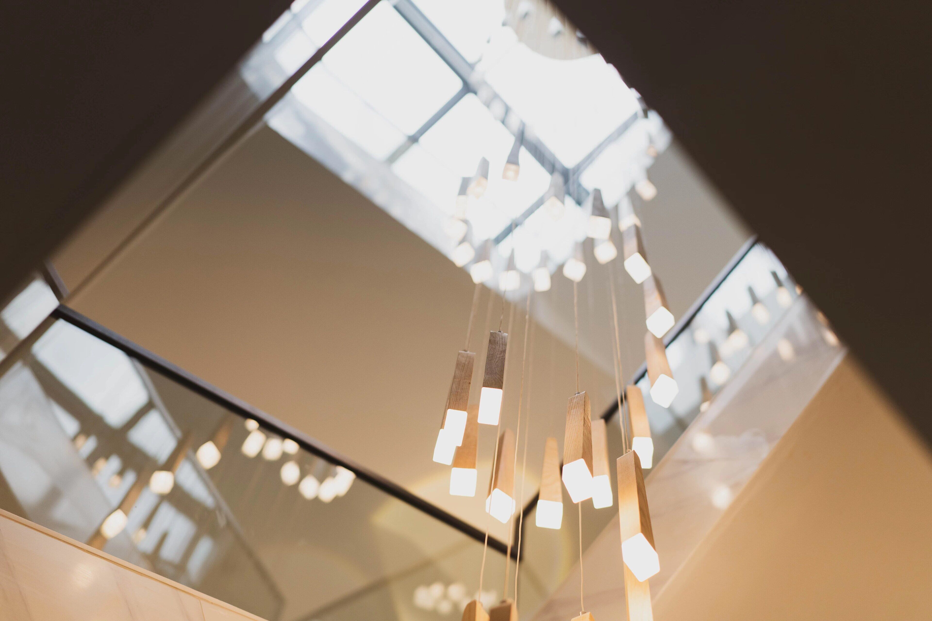 A modern interior with a reflective ceiling and hanging geometric light fixtures.