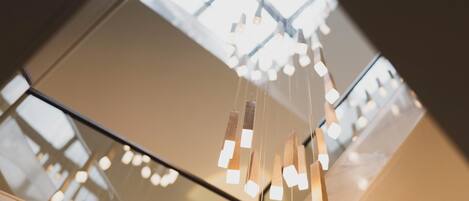 A modern interior with a reflective ceiling and hanging geometric light fixtures.