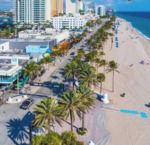Eine Küstenstadt mit Strand, Palmen und modernen Gebäuden.