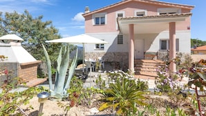 A two-story house with a covered patio, stone steps, and a garden with various plants and a large aloe vera plant. - Villa in Lloret de Mar with Private Pool (Lloret de Mar)