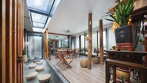 Un interior moderno con techo de vidrio, suelo de madera y una fuente central.