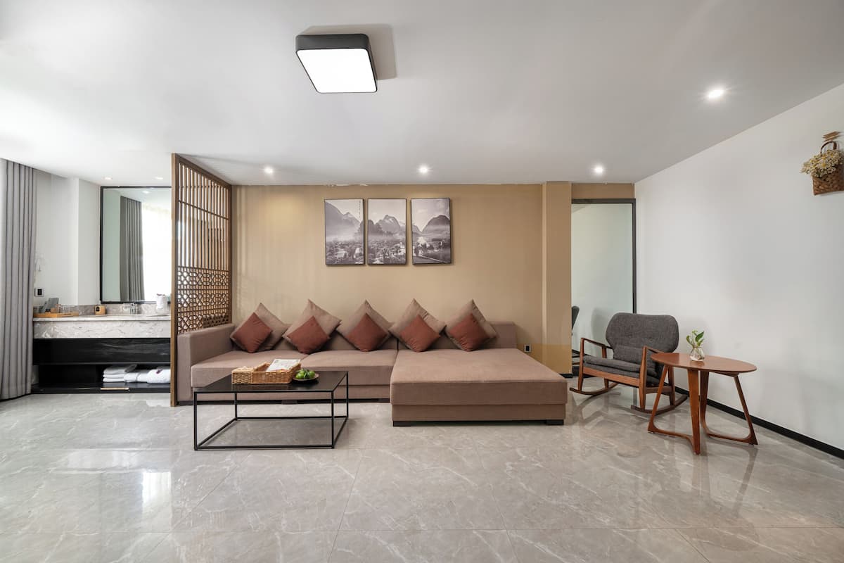 A modern living room with a sectional sofa, a coffee table, a grey armchair, and a small wooden table.