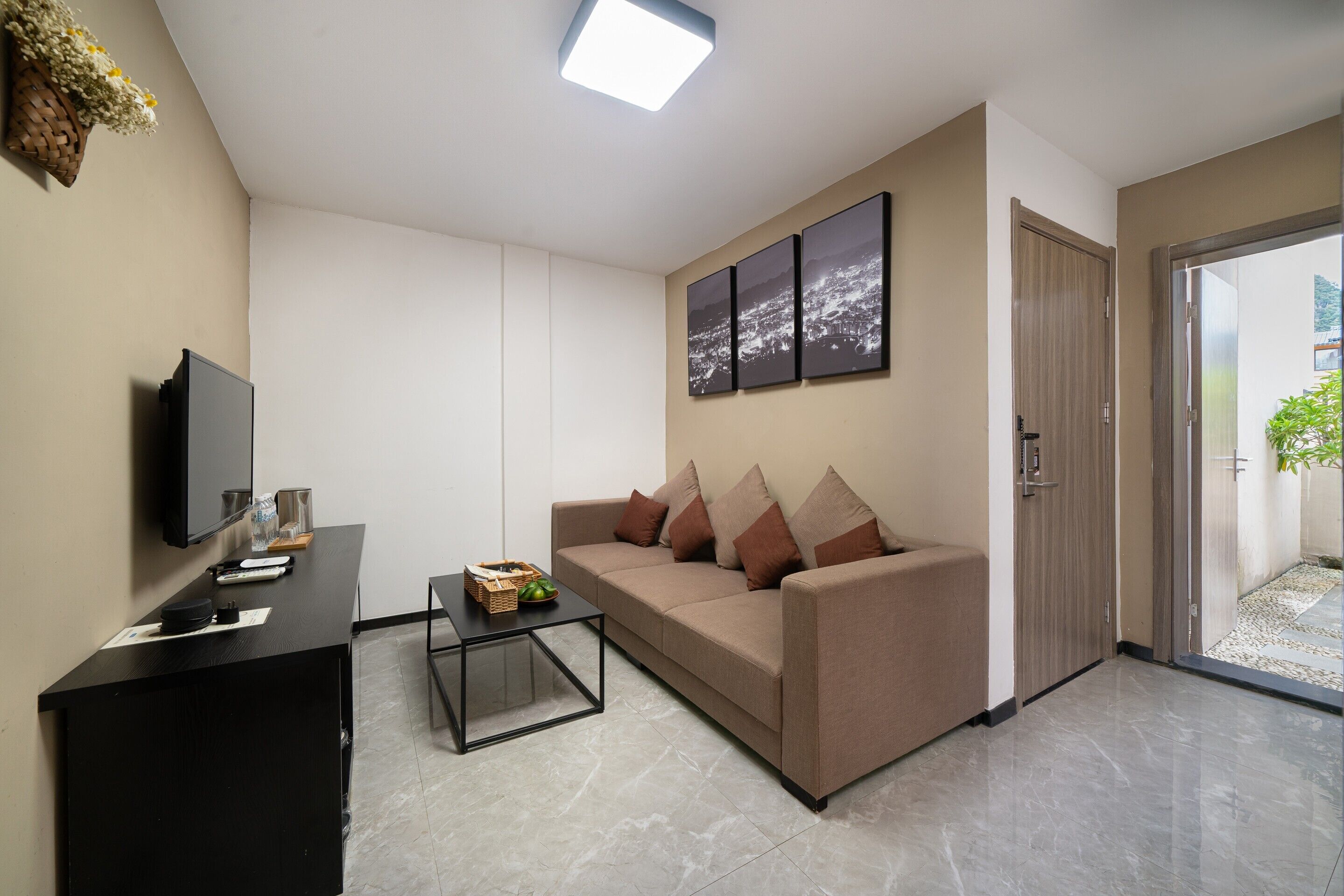 A modern living room with a sofa, a coffee table, a TV, and a door leading to a balcony.