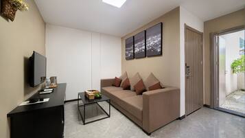 A modern living room with a sofa, a coffee table, a TV, and a door leading to a balcony.