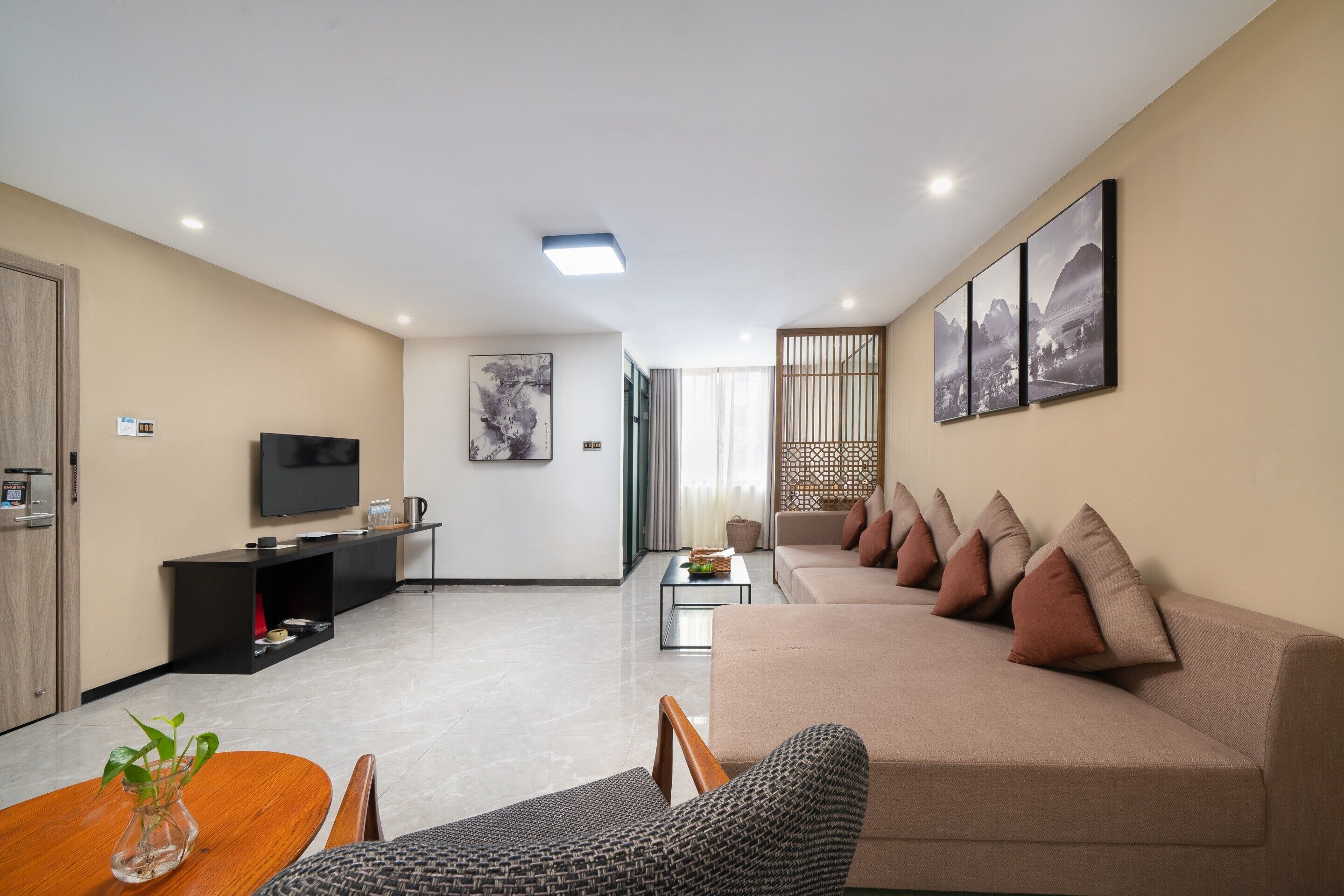 Ein modernes Wohnzimmer mit Sofa, Fernseher, Couchtisch und einem Essbereich mit Tisch und Stühlen.