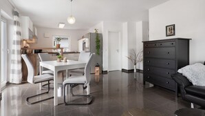 A modern kitchen with a dining area, a black leather sofa, and a large cabinet. - Apartment 'Am Otterbach' with Balcony and Wi-Fi (Jockgrim)