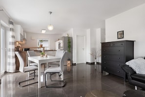 A modern kitchen with a dining area, a black leather sofa, and a large cabinet. - Apartment 'Am Otterbach' with Balcony and Wi-Fi (Jockgrim)