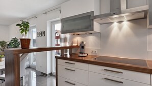 A modern kitchen with a stainless steel range hood, white cabinets, and a wooden countertop. - Apartment 'Am Otterbach' with Balcony and Wi-Fi (Jockgrim)