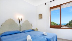 A bedroom with two beds, a nightstand, a candelabra, and a window with a view.