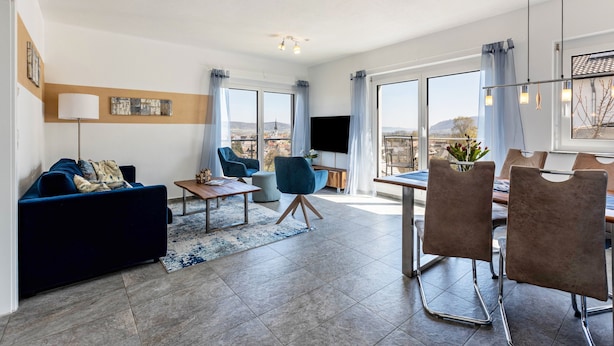 Un salon moderne comprenant un canapé, des fauteuils, une table basse et un coin repas avec des chaises et une table.