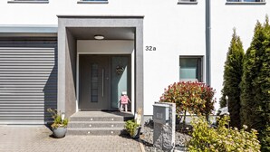Un bâtiment moderne doté d’une porte de garage, d’une entrée avec des marches et d’une boîte aux lettres.