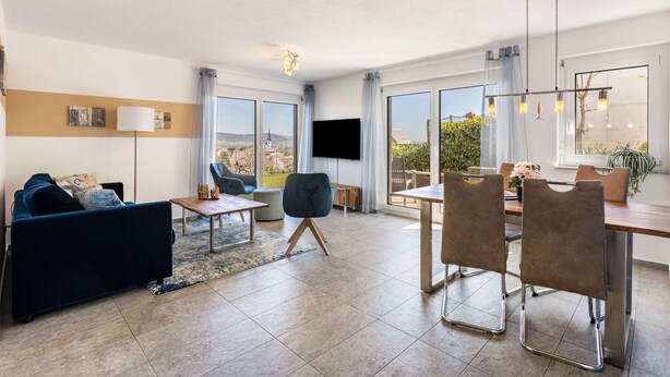 A modern living room with a sofa, chairs, a dining table, and a TV. - Apartment 'Untersee' with Lake View, Private Terrace and Wi-Fi (Stockach)