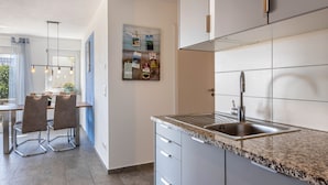 A modern kitchen with a granite countertop, stainless steel sink, and a dining area with a table and chairs. - Apartment 'Untersee' with Lake View, Private Terrace and Wi-Fi (Stockach)