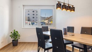 A dining area with a wooden table, black chairs, a potted plant, and a window with a view of buildings. - Apartment 'Winder 1' with Mountain View and Wi-Fi (Lustenau)