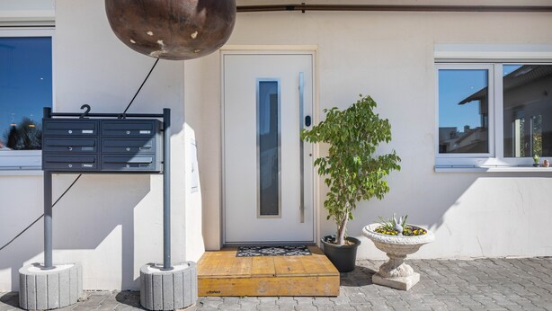 A building entrance with a mailbox, a door, a potted plant, and a small garden feature. - Apartment 'Winder 1' with Mountain View and Wi-Fi (Lustenau)
