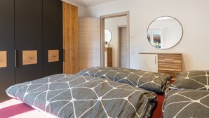 A bedroom with a bed, a wardrobe, a mirror, and a door leading to another room. - Apartment 'Winder 1' with Mountain View and Wi-Fi (Lustenau)