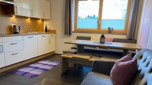 A modern kitchen with white cabinets, a wooden countertop, and a window with curtains. - Apartment 'Mario' with Mountain View, Private Terrace and Wi-Fi (Hippach)