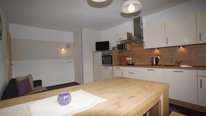 A compact kitchen with white cabinets, a wooden countertop, a microwave, an oven, and a sink. - Apartment 'Mario' with Mountain View, Private Terrace and Wi-Fi (Hippach)
