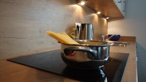A modern kitchen with a stainless steel pot on an induction cooktop, a wooden countertop, and a visible sink. - Apartment 'Mario' with Mountain View, Private Terrace and Wi-Fi (Hippach)