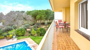 Ein Balkon mit Pool, Sitzgelegenheiten im Freien und Blick auf einen angelegten Garten.