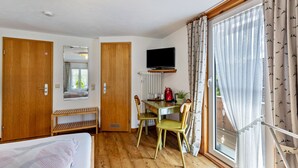 Ein Zimmer mit einem Bett, einem Schreibtisch mit Stuhl, einem Fernseher und einem Fenster mit Vorhängen.