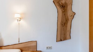 Ein Zimmer mit einem Bett, einer Wandlampe und einem großen Holzboden an der Wand.