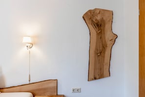 Et værelse med en seng, en væglampe og et stort træelement på væggen.