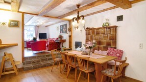 A wooden dining table with chairs, a chandelier, and a fireplace.