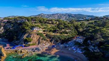 Un pueblo costero con playa, acantilados rocosos y casas en la ladera.