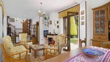 A cozy living room with a fireplace, wooden furniture, and a dining area with a table and chairs.