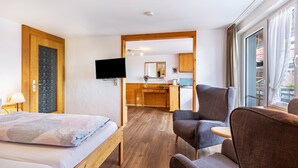 A hotel room with a bed, a desk, a chair, a television, and a view of the outside. - Studio Apartment 'Apartment 2' with Shared Garden, Balcony and Wi-Fi (Donaueschingen)
