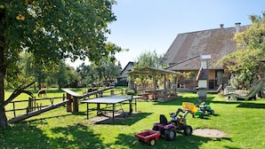 A grassy outdoor area with a wooden table, a covered seating area, and a tractor. - Studio Apartment 'Apartment 2' with Shared Garden, Balcony and Wi-Fi (Donaueschingen)