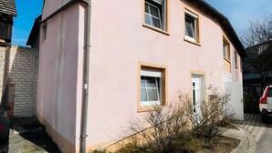 A pink building with two windows and a garage door, adjacent to a paved road. - Apartment 'D Haus' with Wi-Fi (Arnstein)