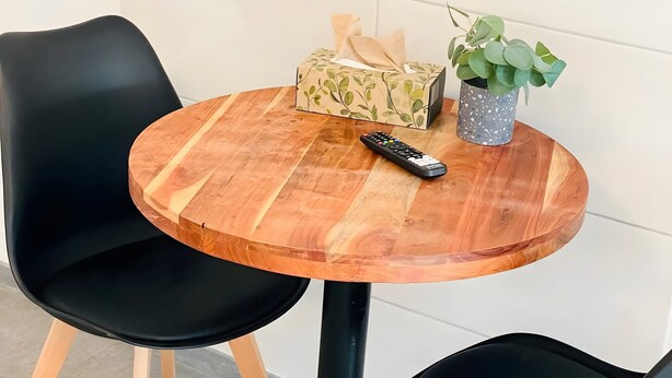 A round wooden table with a black remote control, a tissue box, and a potted plant. - Apartment 'D Haus' with Wi-Fi (Arnstein)