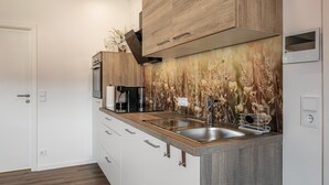 Una cocina moderna con armarios de madera, un lavamanos de acero inoxidable y un salpicadero decorativo.