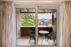 Un balcon avec une table et des chaises, une vue sur une colline et un plafond en bois.