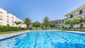 A swimming pool with clear blue water, surrounded by well-maintained greenery and buildings with balconies. - Apartment in Calella near Sand Beach (Calella de Palafrugell, Llafranc)