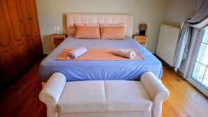 Een slaapkamer met een bed, nachtkastjes, een houten garderobe en een raam met gordijnen.