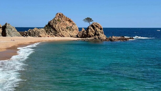 Uma praia com formações rochosas e água azul cristalina.