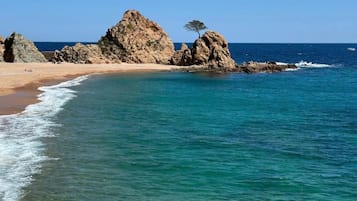 A beach with rocky formations and clear blue water.