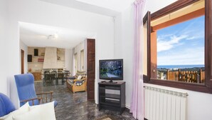 Sala de estar com televisão, sofá, mesa de centro e vista para o exterior.