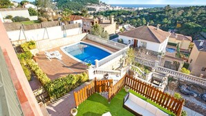 Uma piscina no terraço com deck de madeira, área de estar e vista do bairro ao redor.
