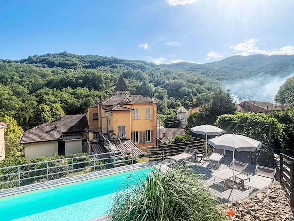 A pool area with lounge chairs and a view of a mountain landscape.