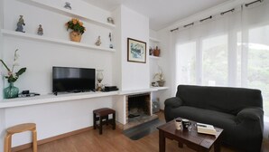 Uma sala de estar com lareira, televisão, sofá e mesa de centro.